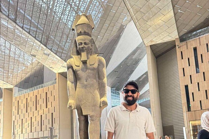 A large ancient Egyptian statue in a modern building with a glass ceiling. 1