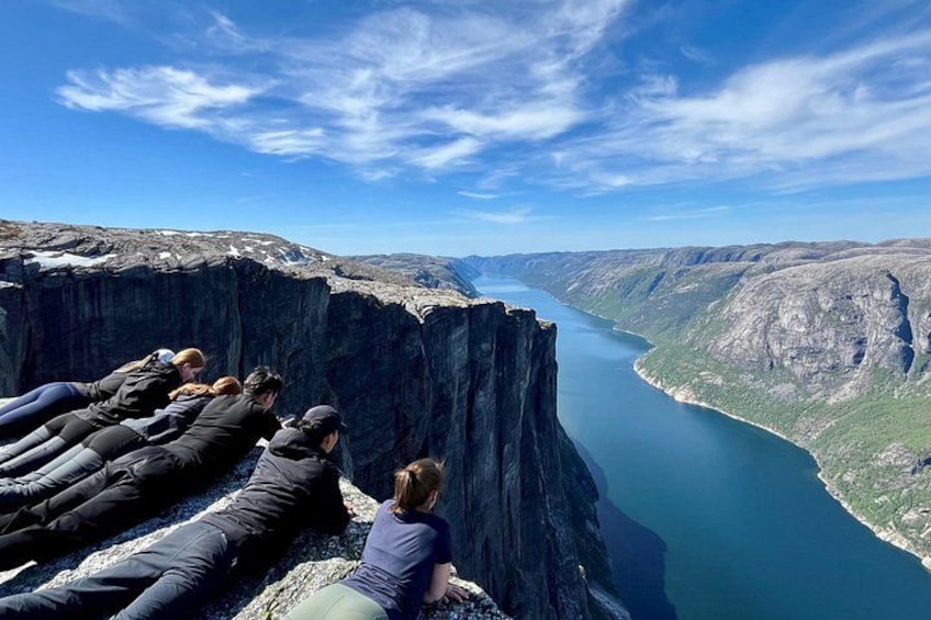 Un gruppo di persone sedute su una scogliera con vista su un profondo canyon e un fiume. 1