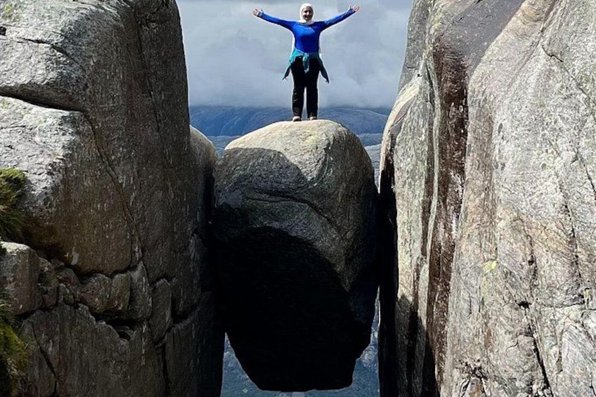 Una persona in piedi su una roccia con le braccia aperte tra due imponenti formazioni rocciose. 4
