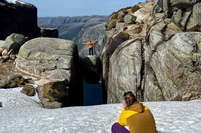 Una persona con un giubbotto giallo seduta sulla neve, con una scogliera rocciosa sullo sfondo. 3