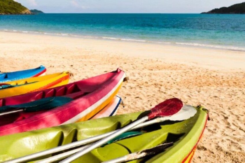 A beach with colorful kayaks and paddles. 3