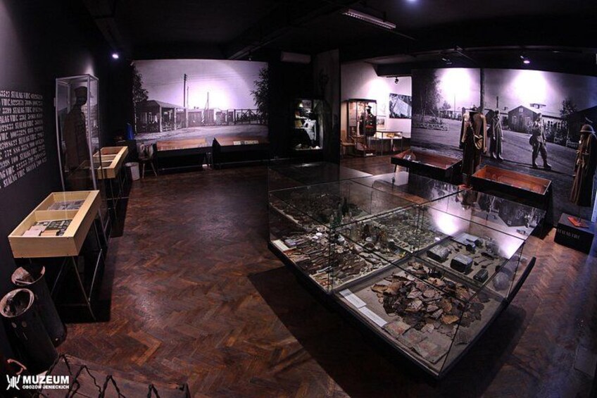 An indoor museum exhibit with glass display cases, wooden flooring, and wall-mounted informational panels. 2