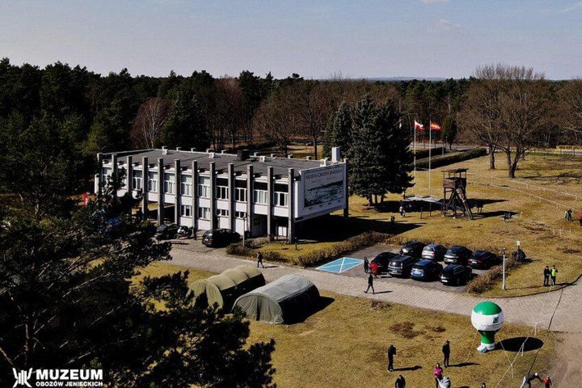 A museum building with a parking lot, tents, and a flagpole. 4