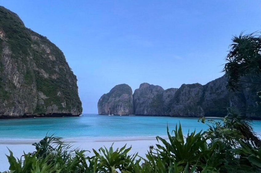 A beach with clear turquoise water, white sand, and limestone cliffs. 3