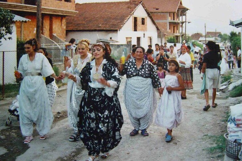 Eine Gruppe von Menschen in traditioneller Kleidung geht auf einem Feldweg. 1