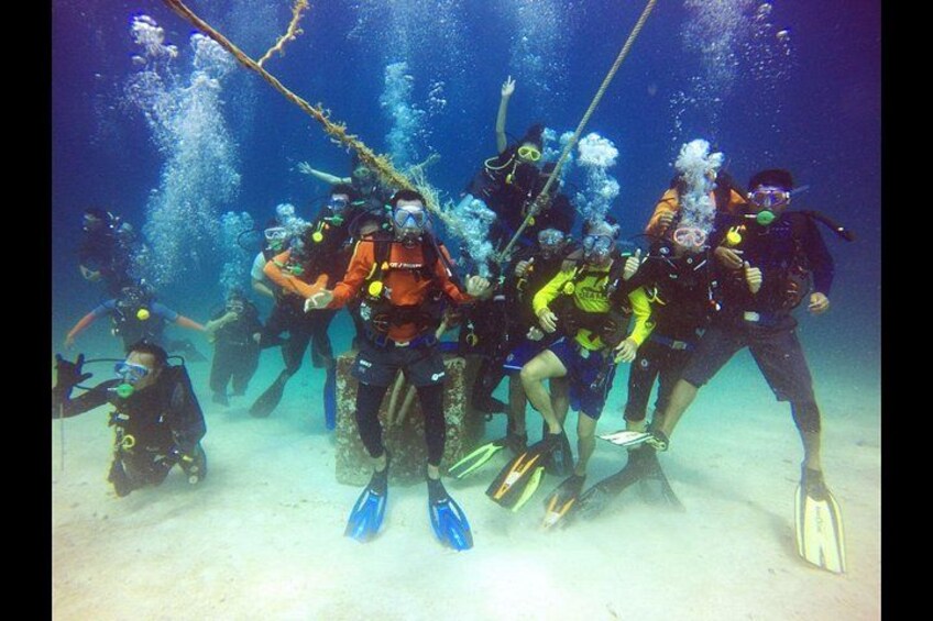 Un grupo de buzos bajo el agua, rodeados de burbujas y aletas. 5