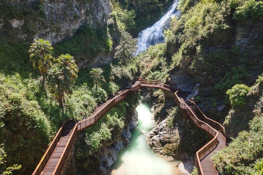 A wooden bridge over a river, surrounded by lush greenery and a waterfall. 1