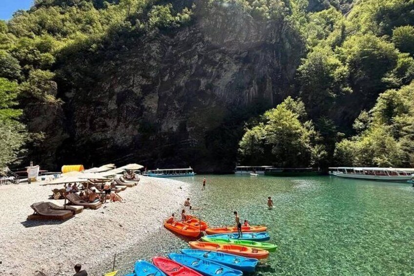 Una playa con barcos, un acantilado rocoso y agua cristalina. 2