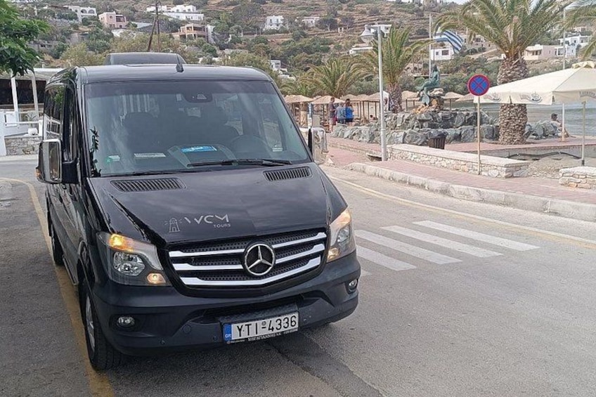 A black Mercedes-Benz van parked on a street with a coastal background. 4