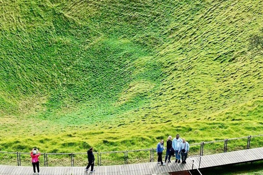 A grassy hill with a wooden walkway and people standing on it. 2