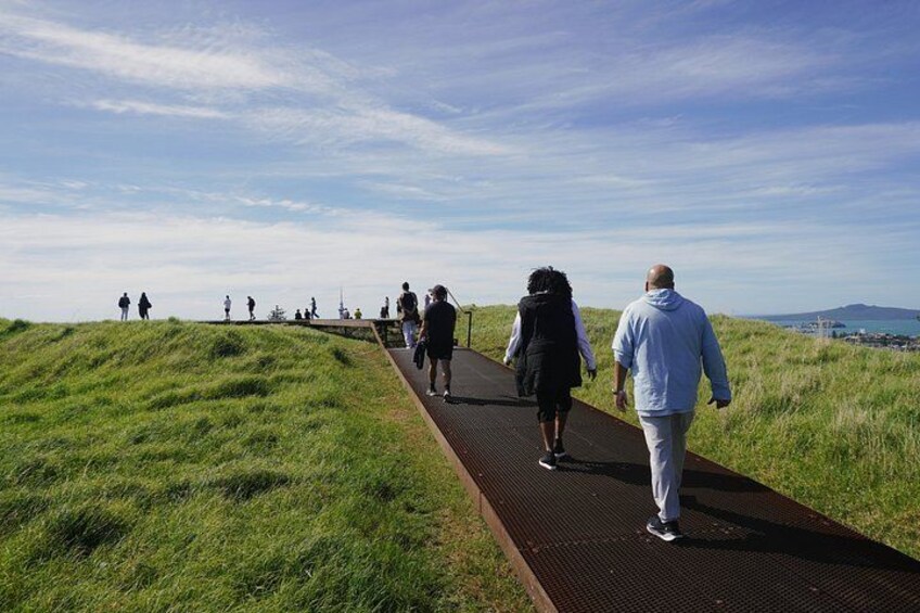 A pathway with people walking on it, surrounded by grassy fields and a clear sky. 4