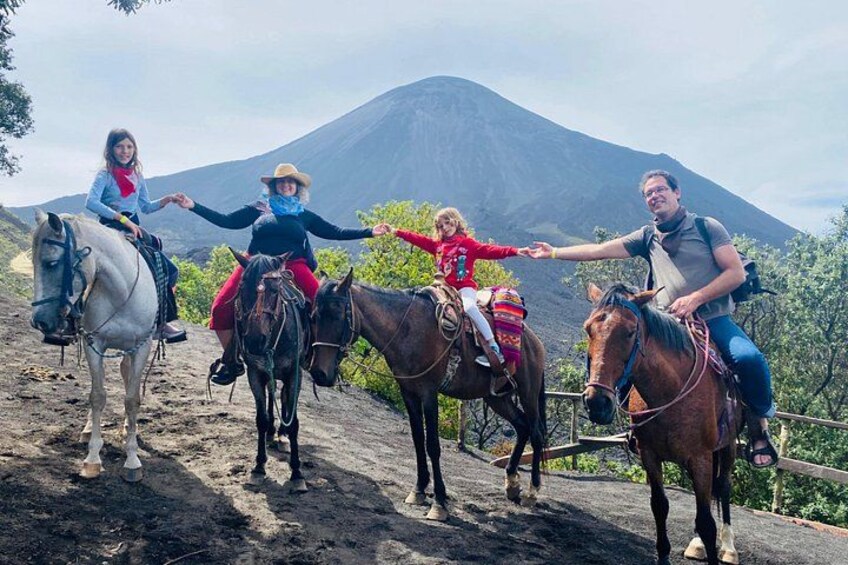 Three people riding horses on a dirt path with a mountain in the background. 3