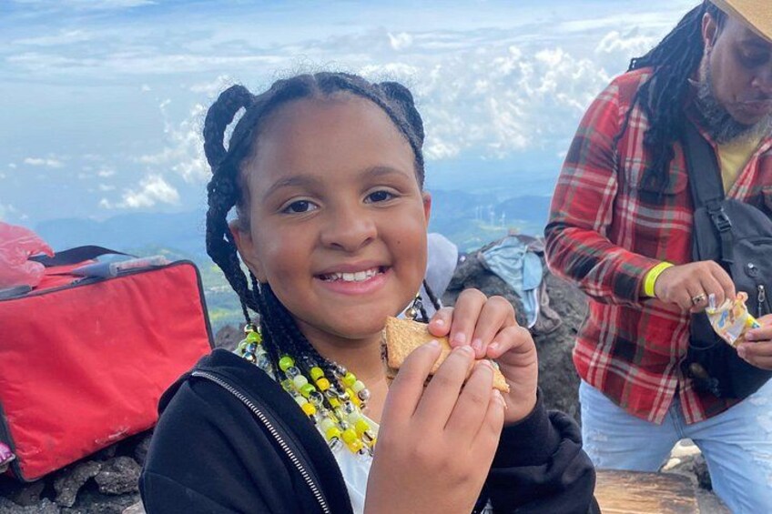 A person eating a snack outdoors with a mountainous landscape in the background. 5