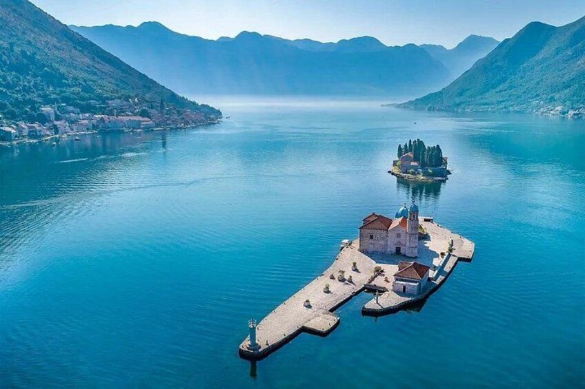 A lake with a pier, a small island with a church, and mountains in the background. 5