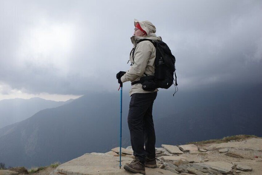 A hiker on a rocky mountain peak with a cloudy sky. 2