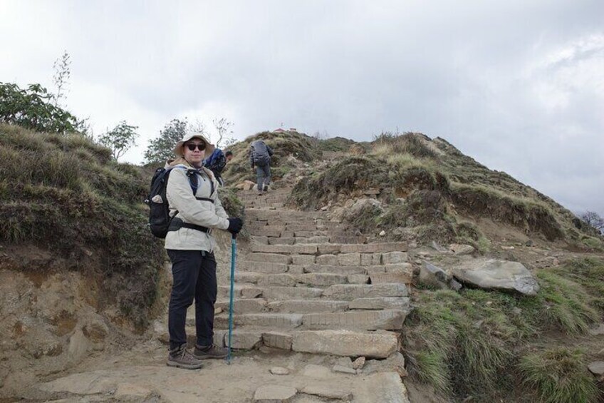 A hiker on a stone staircase with a backpack, surrounded by grassy terrain and other hikers in the background. 3