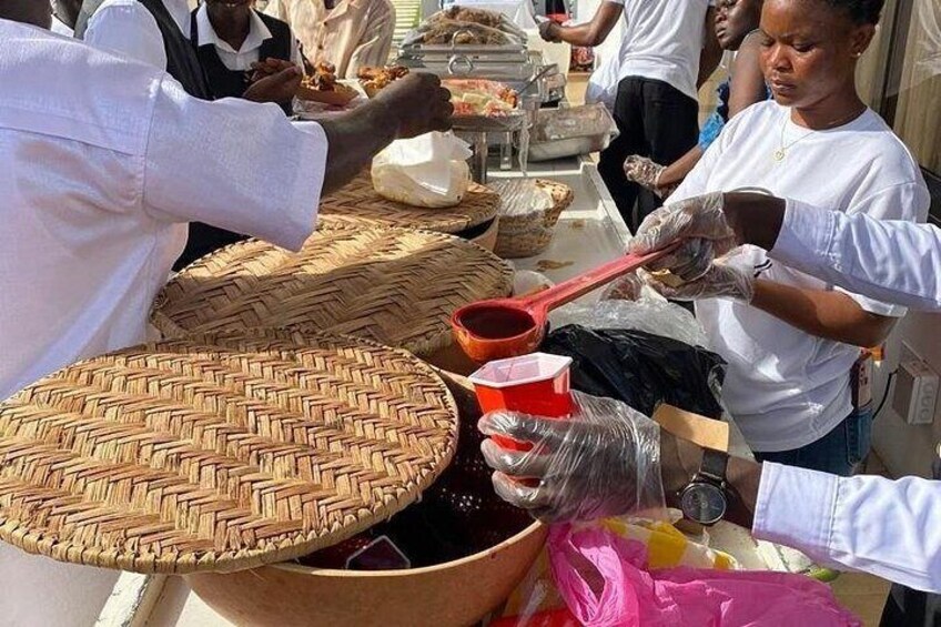 People serving food at a market stall with woven baskets and plastic containers. 1