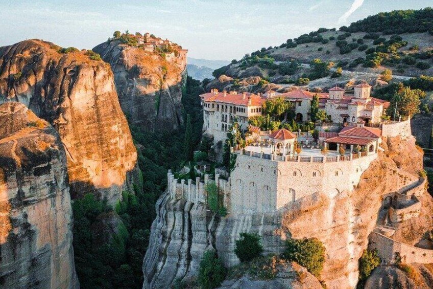 A monastery perched on a cliffside, surrounded by rocky terrain and a valley. 2