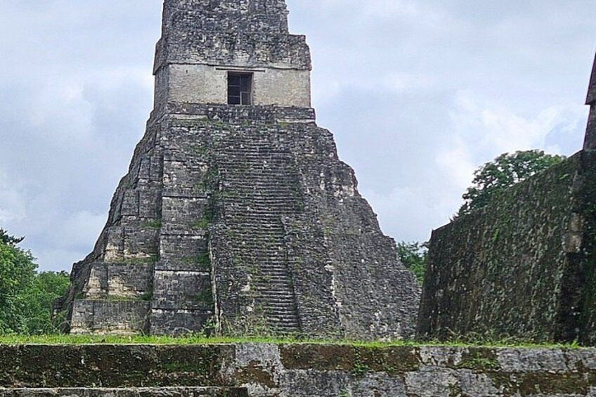 A large, ancient stone pyramid with a narrow entrance at the top, surrounded by lush greenery. 2