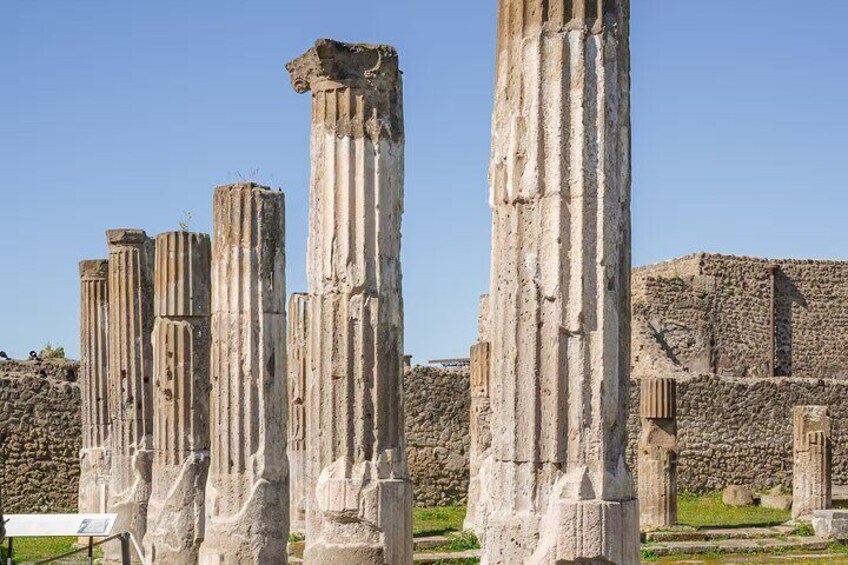Ancient stone columns with a stone wall in the background. 1