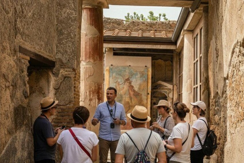 A group of tourists gathered around a guide in an ancient building with classical architecture. 3