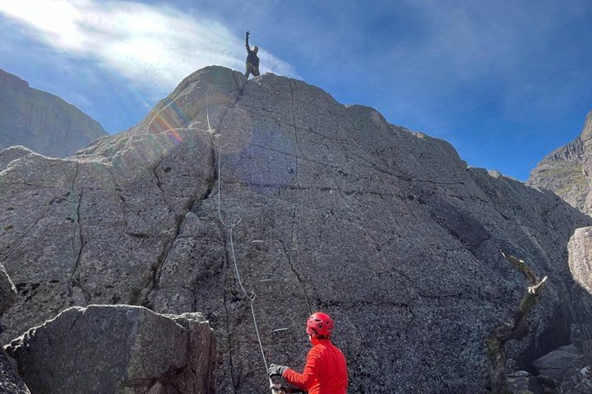 A person in a red jacket climbing a rocky mountain. 3