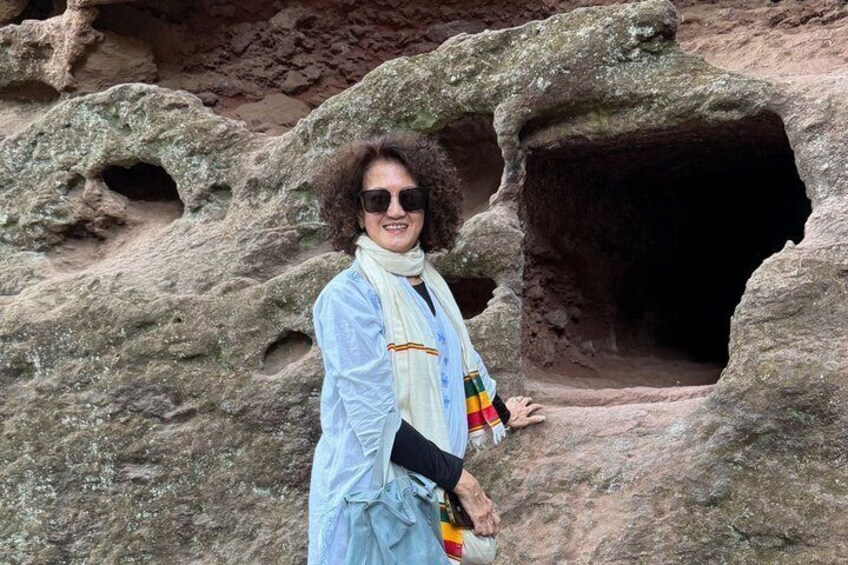 A person standing in front of a rocky cave entrance. 3