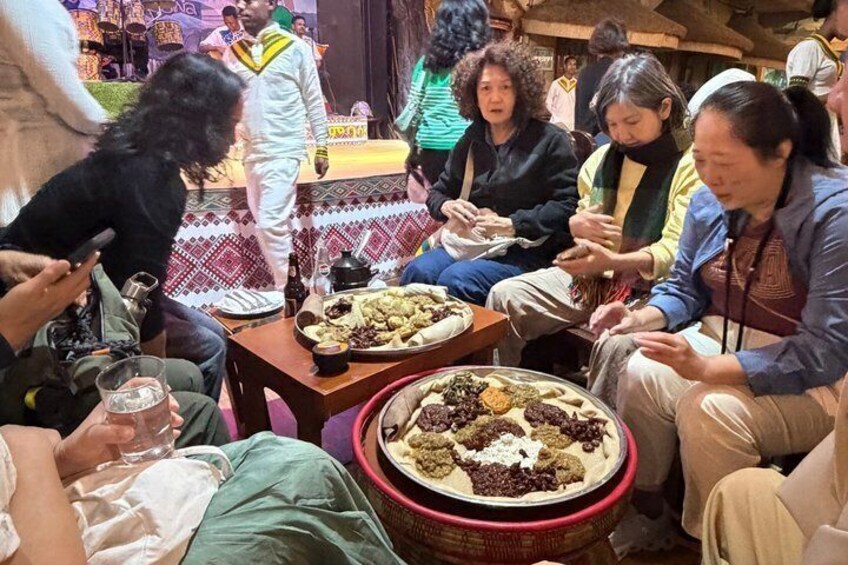 A group of people sitting around a table with various dishes. 2