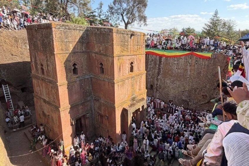 A crowd gathered around a large brick structure with a flag on top. 4