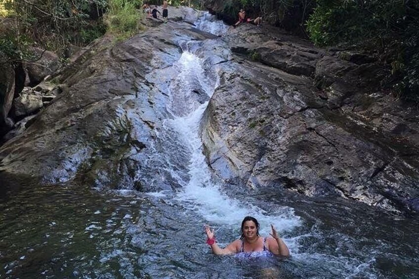 Een waterval die over rotsen stroomt, met een persoon in het water. 3