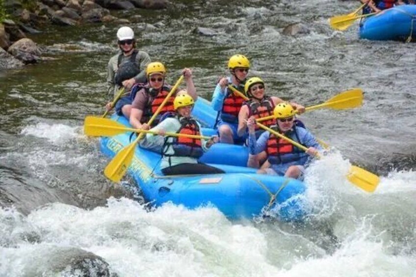 Un gruppo di persone su una zattera blu che naviga un fiume con rapide. 3