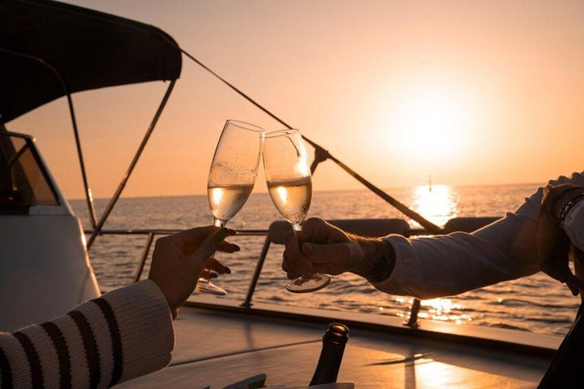 Two people toasting with wine glasses on a boat at sunset. 2