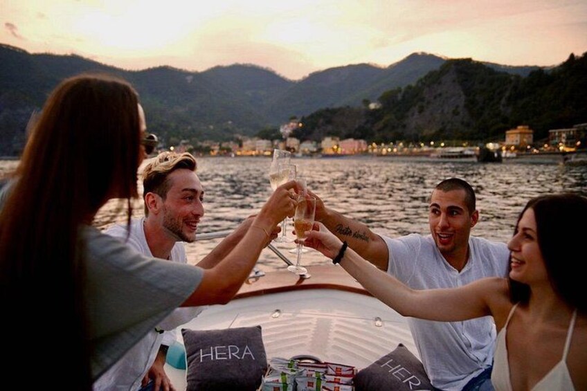 A group of people toasting with champagne glasses on a boat with a mountainous backdrop. 4