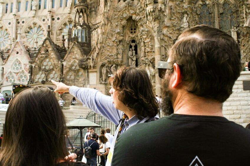A group of people observing a detailed architectural structure with intricate designs and pointed arches. 5