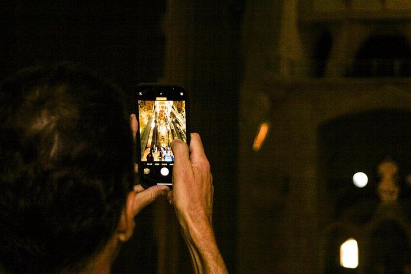 A person holding a smartphone, capturing an image of a building with a staircase. 3