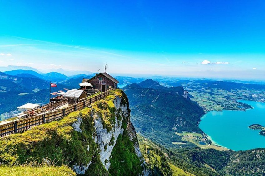 A mountain viewpoint with a wooden structure, a lake, and surrounding hills. 4
