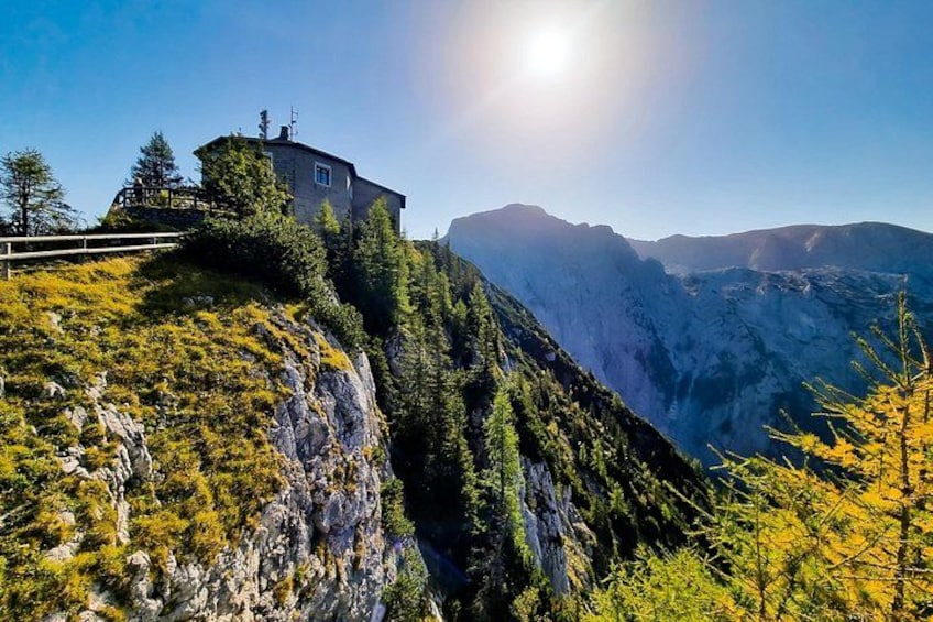 A mountain house on a cliff, surrounded by trees and a valley. 3