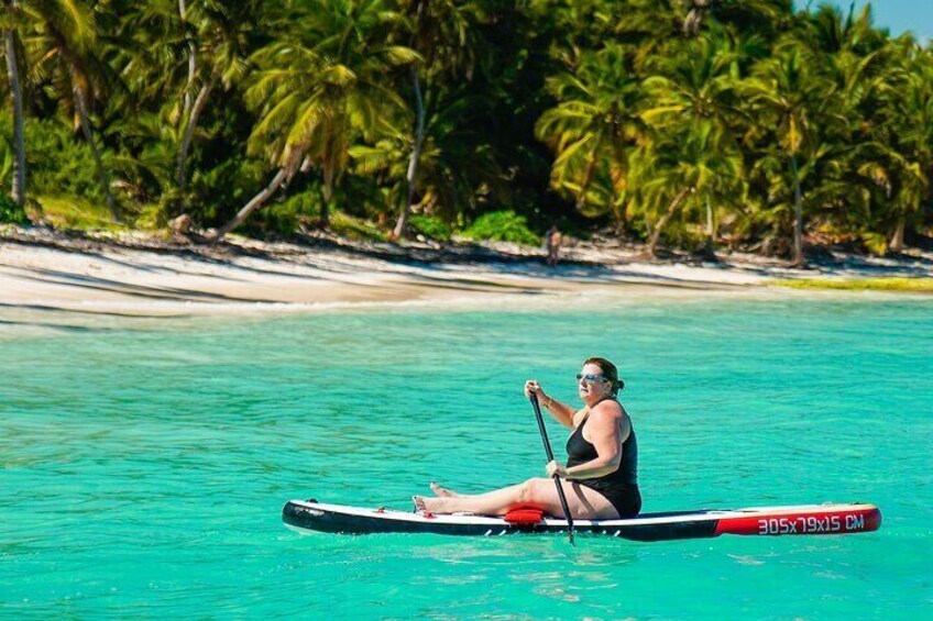Une personne fait du paddle sur une eau turquoise, avec des palmiers et une plage en arrière-plan. 5