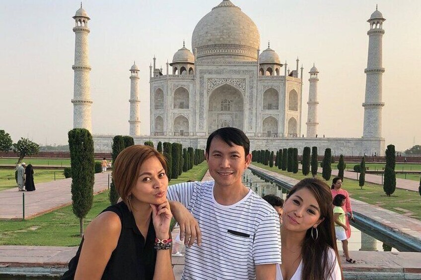 Three people posing in front of the Taj Mahal. 1