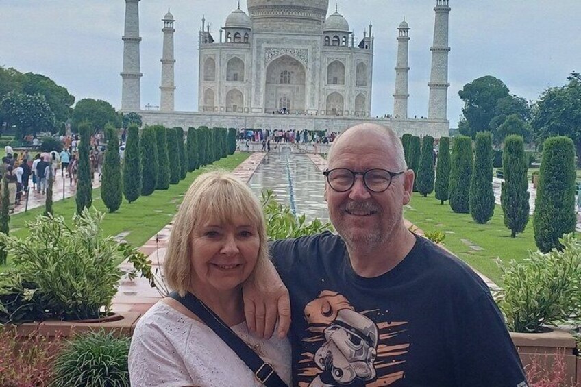 A couple in front of the Taj Mahal with its iconic minarets and the Charbagh garden. 2