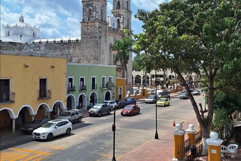 Una calle con coches aparcados, una iglesia y una torre. 3