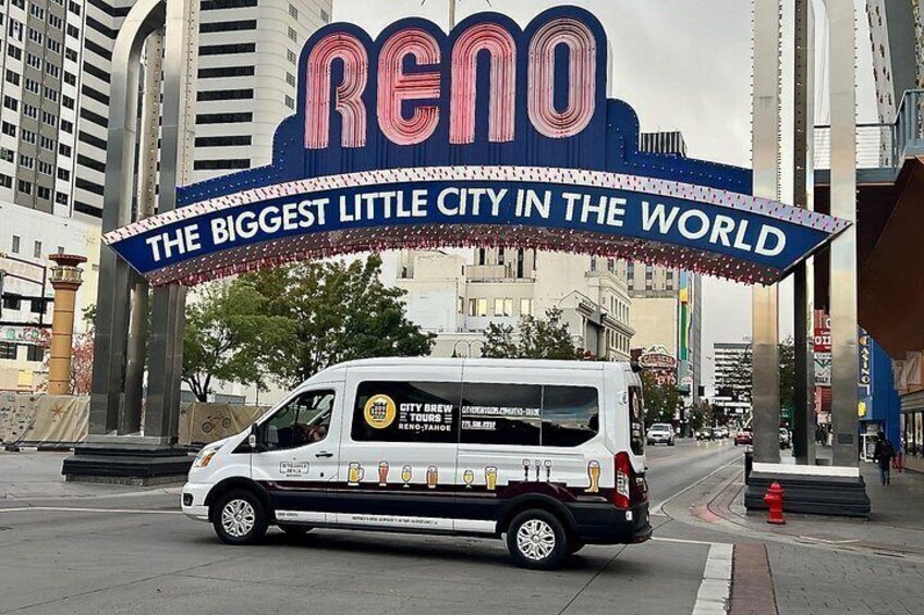 A van with 'City Brew' branding parked under a large Reno sign. 1