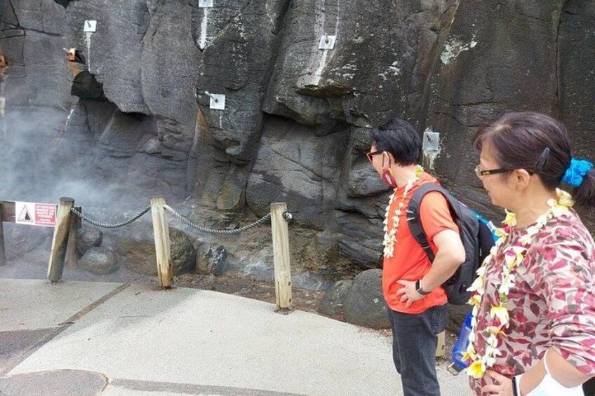 A rocky cliff with safety signs and a chain barrier. 3