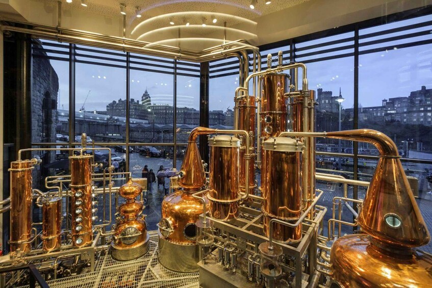 A distillery with copper stills and a cityscape view through large windows. 3