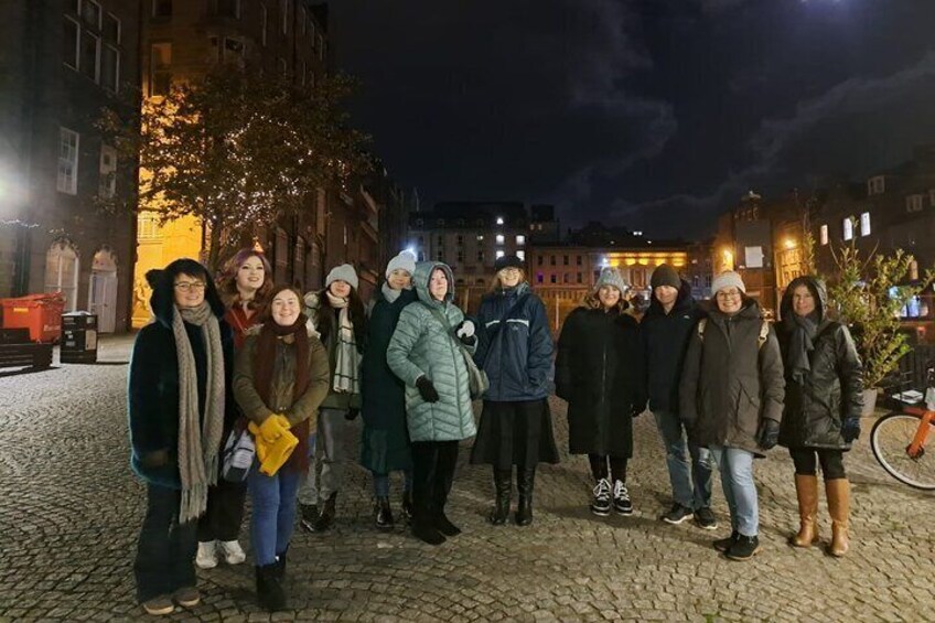 Un grupo de personas de pie en una calle empedrada de noche. 1