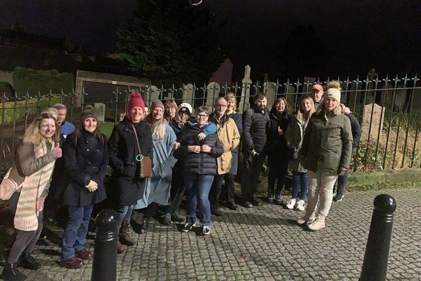 Un grupo de personas de pie sobre un camino adoquinado de noche. 3