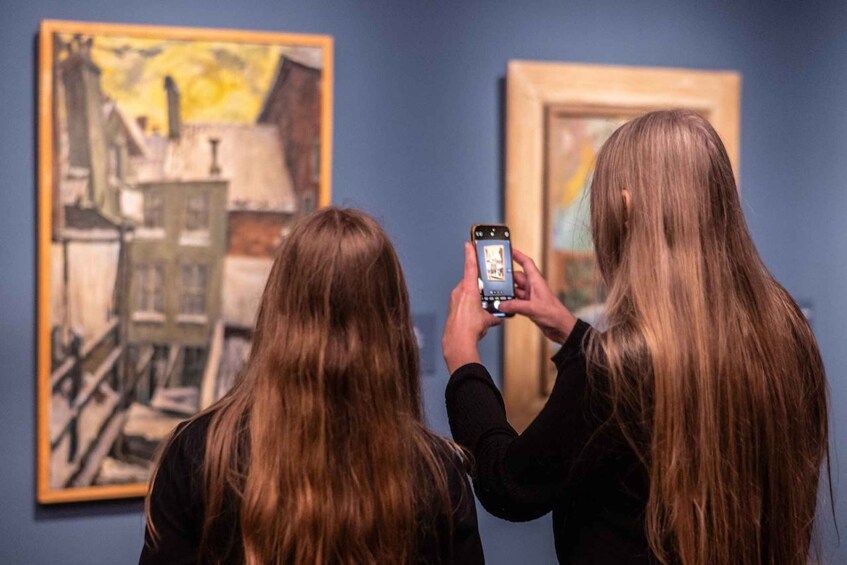 Two people taking a photo of a painting. 2