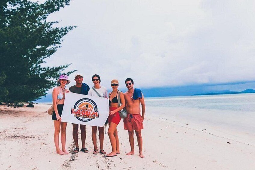 A group of people on a beach holding a sign. 3