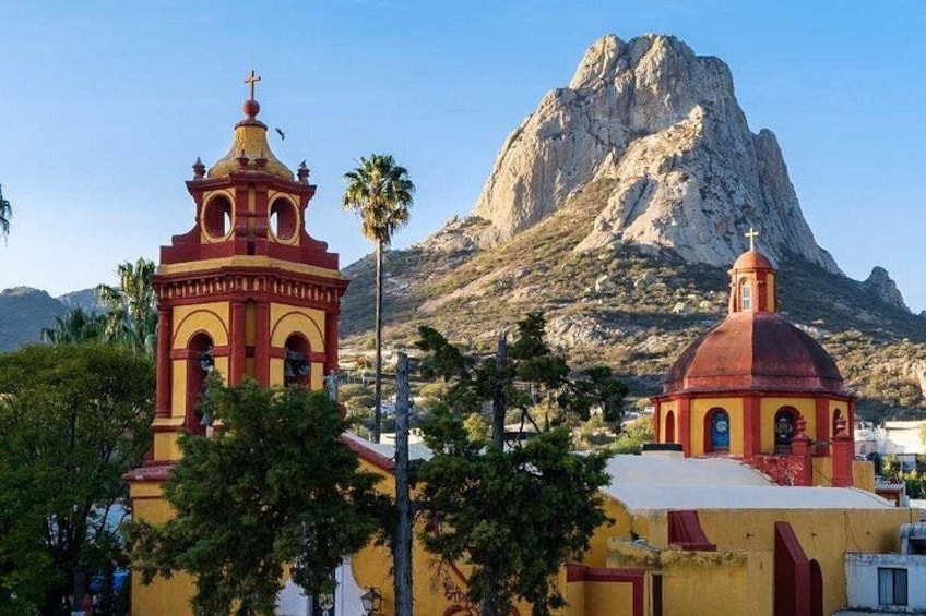 A church with a bell tower and a mountain in the background. 1