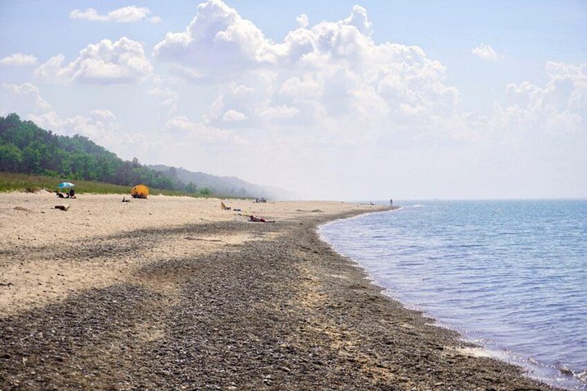 A beach with a rocky shoreline, a clear sky, and distant mountains. 2